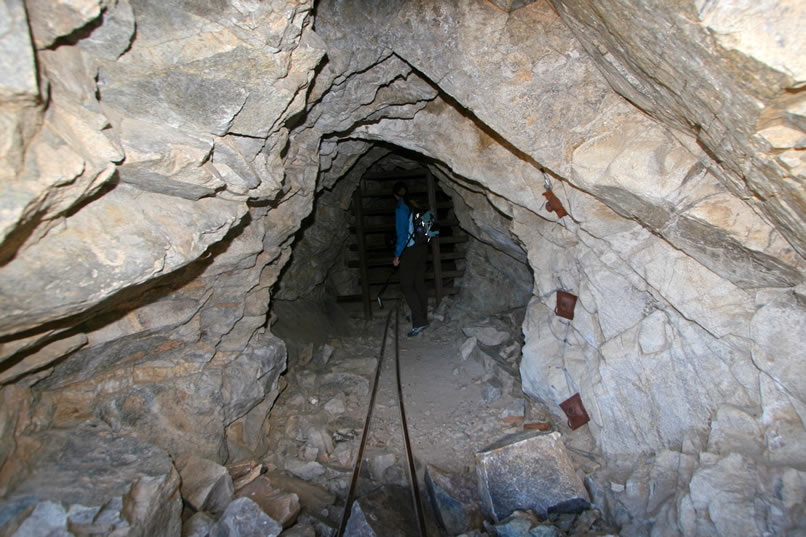 Several mine tunnels enter the hillside from along the trail.  They all have sturdy grates to block access.  In the next photo, taken through the grate, you can see that the twisted rails continue into the depths of the hillside.