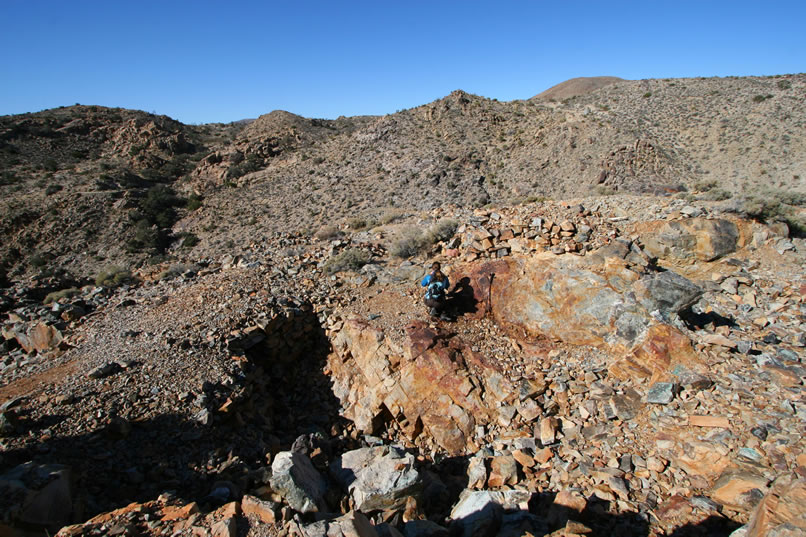 Finally, we climb to the top of the mine area and find some prospect pits and grated shafts.  As you can see in the next photo, many of the rocks here are coated with colorful copper minerals.
