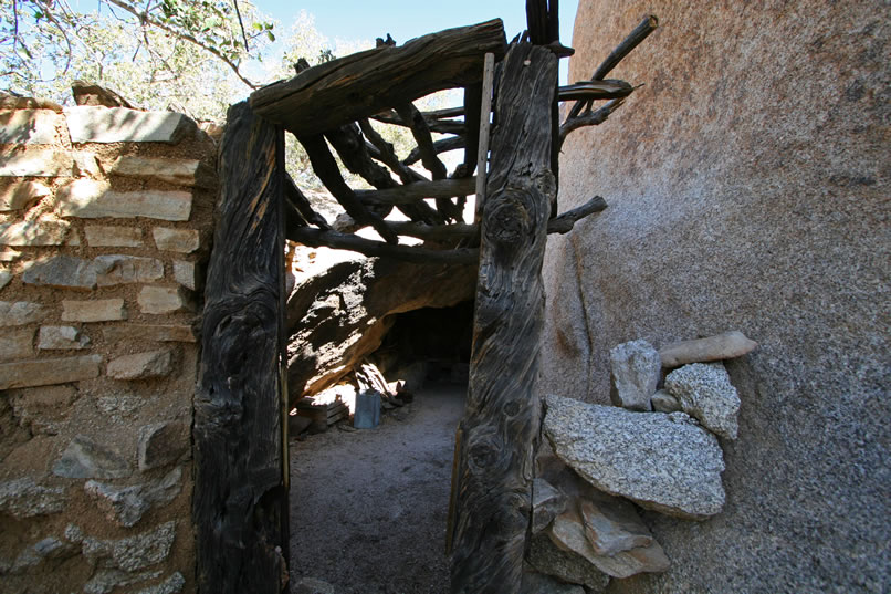 Even though we visited the rockshelter cabin on a previous trip, we decide to check it out again before dropping down into the canyon below in search of the lower mine workings.  The entrance itself, seen here, is in poor shape, but in the following photos you can see that as we move deeper into the protection of the massive boulders, the little structure is still intact and snug and cozy.