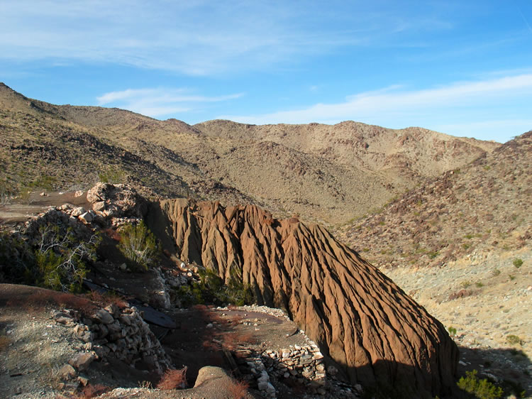 A side view of the tailings.  Notice the bottom of a large tank on the rock pad in front of the tailings.  The top of the tank can just be seen to the left of the pad.