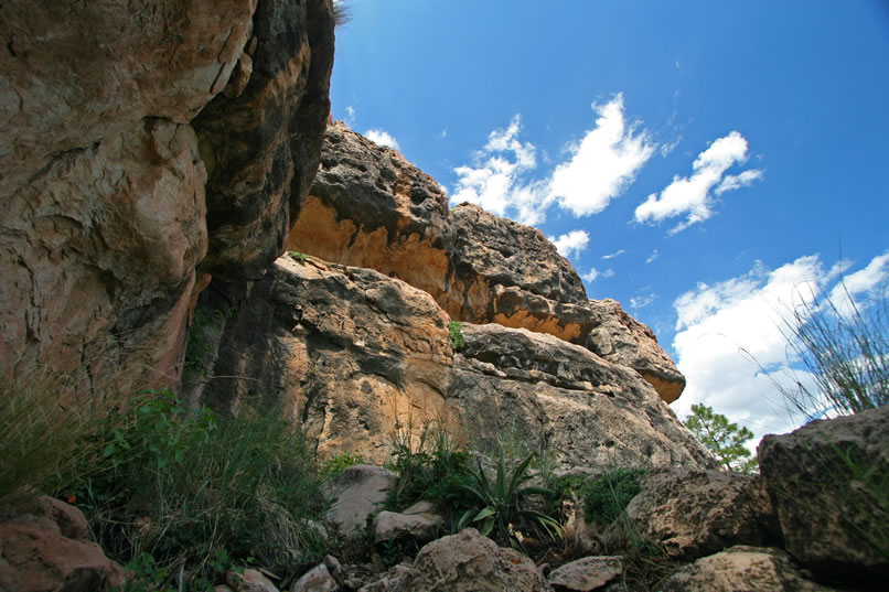 Niki finds that by slithering all the way to the end of the crevice and then gingerly shuffling along a narrow ledge, she's able to access a second pictograph panel high on the next cliff face that you see here.