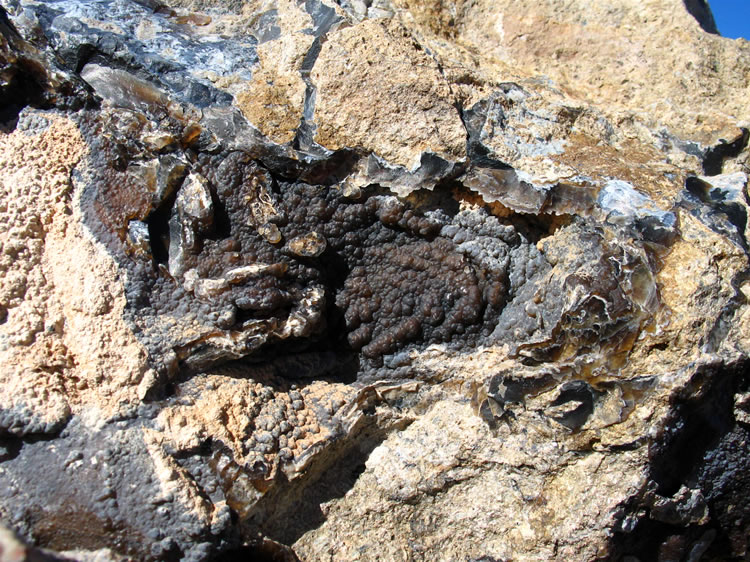 Thin veins and plates of copper colored bubbly chalcedony thread their way through the rocks here.