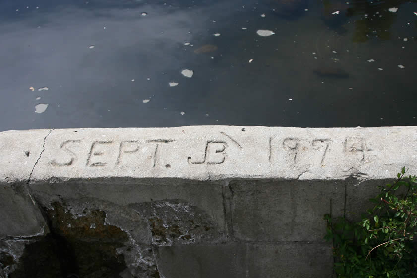 A date and a cattle brand is pressed into the concrete lip of each of the tanks.