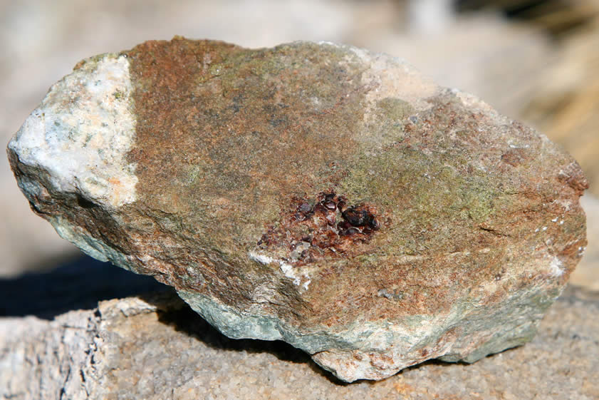 This rock has a much larger garnet crystal cluster on it.