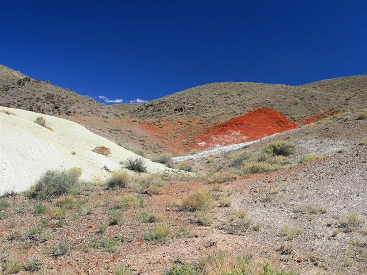 At the summit there are several areas of rich brick red earth juxtaposed with stark white.  From here we drop down onto the eastern flanks of the Silver Peak Mountains and make our way to the Blanco Mine.