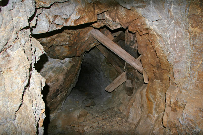 Further into the tunnel we come to an obstacle.  The wooden timbers to the right come from an inclined shaft that drops down from the hillside above and intersects our tunnel.  The problem is that this shaft drops right through the floor of our tunnel and continues on down into the mountain.  So at this point timbers have been placed over the gaping shaft.  They don't inspire confidence and to make matters worse, dirt and rocks have found their way down the shaft to give this walkway a steep camber that tilts toward the dark mouth below.