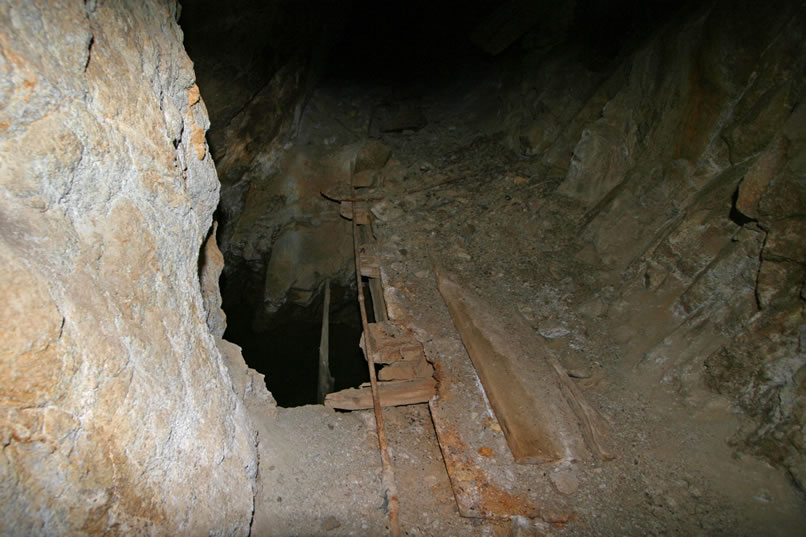 Here's a look at the timbers with their off camber rock fall and the mouth of the shaft below.  Oh, we forgot to mention that the shaft below is filled with water to within a couple of feet of the top.  If one were to fall in there they might not make it out again.