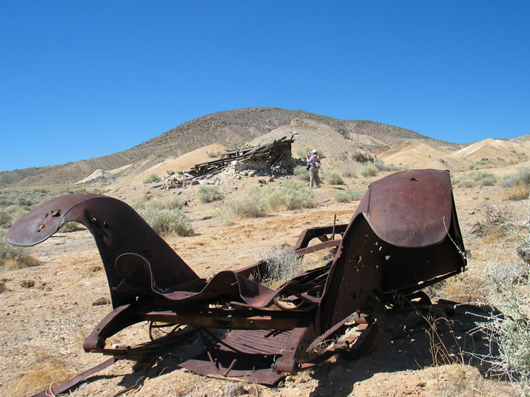 An old car frame lies not far from the wood structure.