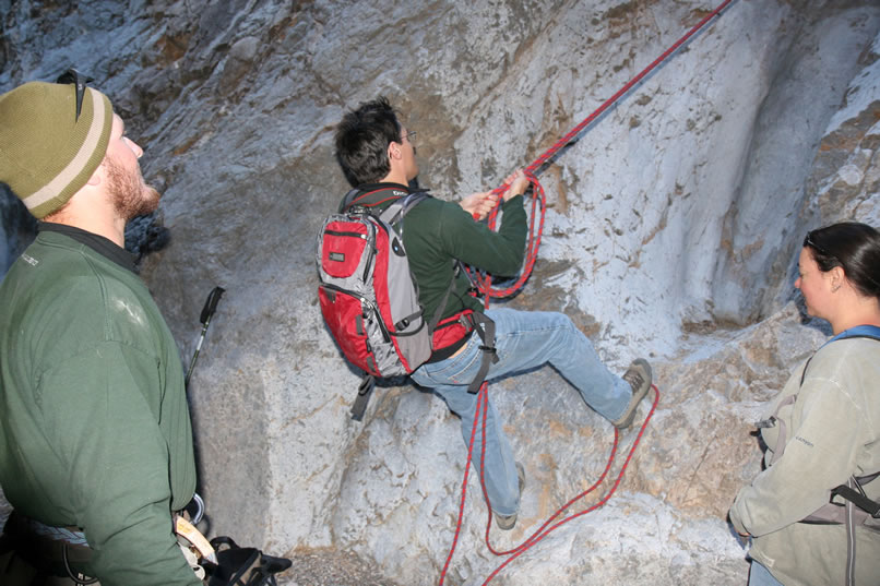 Using cams, wedges and carabiners, Micah has belayed the upper end of the rope.  Here Guy gives it several serious tugs to be sure it's solid.
